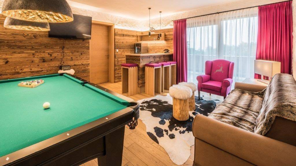 Unterhaltungsraum mit Billardtisch, Holzvertäfelung und gemütlicher Sitzecke.