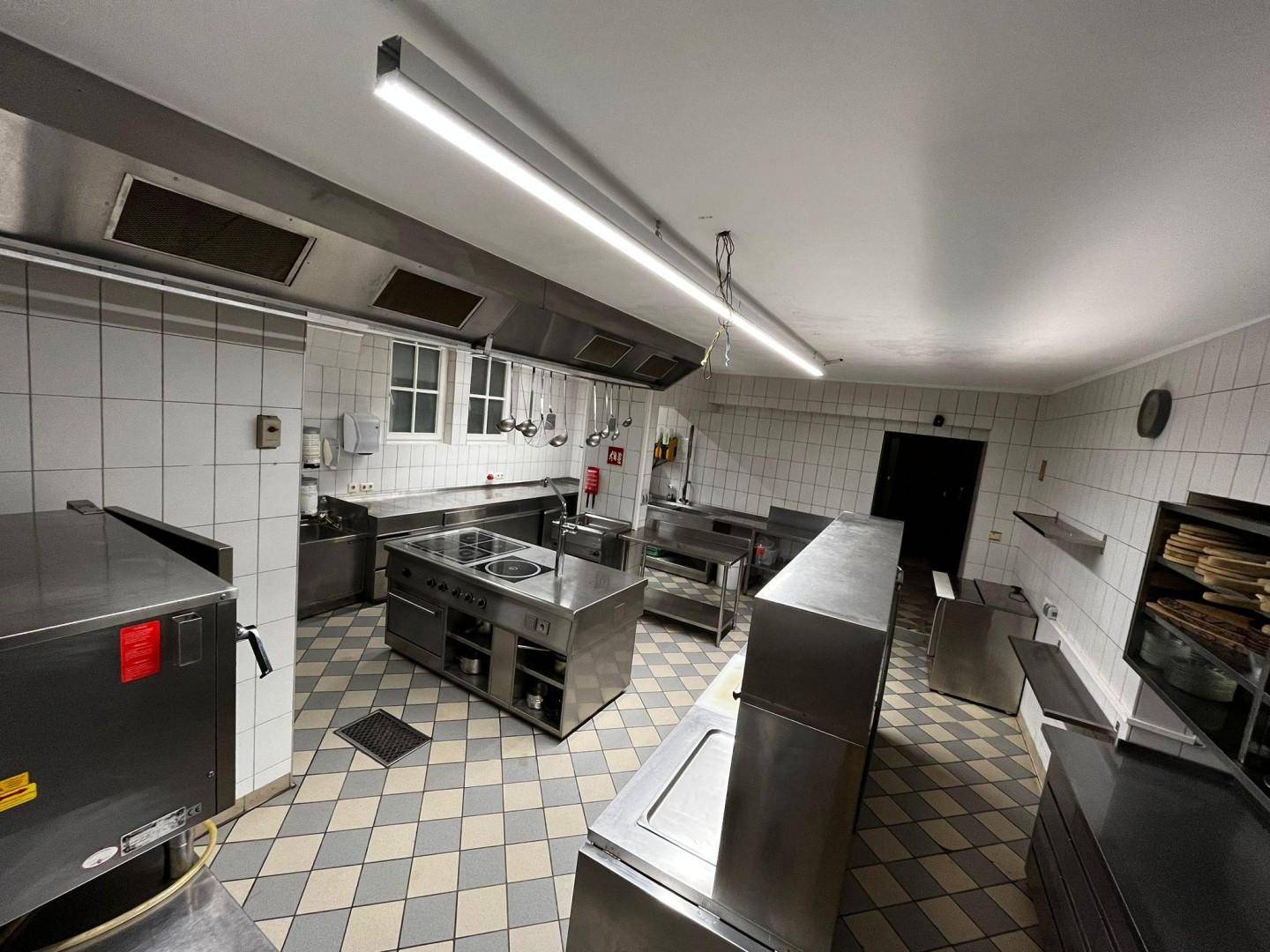 Weitläufige Gastroküche mit modernen Edelstahlgeräten, Kochinsel und guter Beleuchtung.