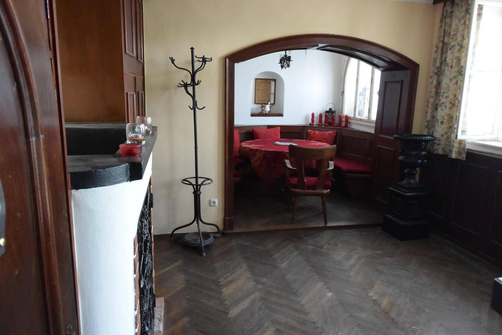 Kleinerer Gastraum, das "Stüberl", mit Fischgrätparkett, roter Tischdecke und traditionellen Holzmöbeln.