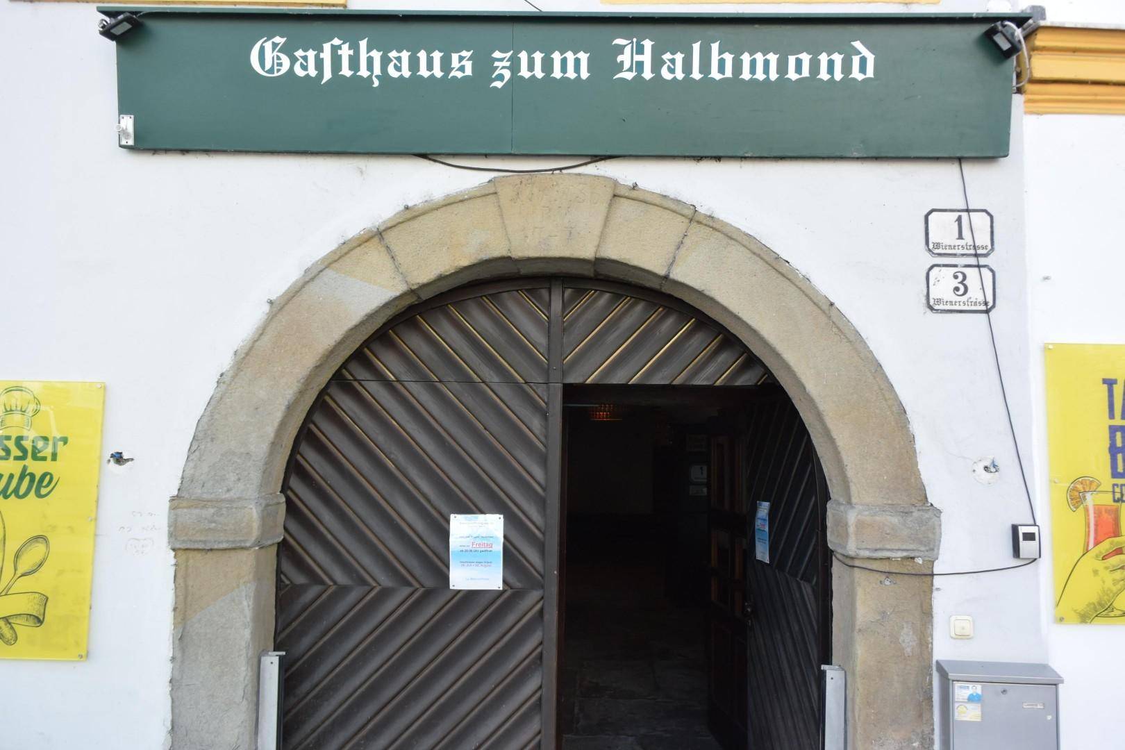 Detailansicht des Haupteingangs zum Gasthaus mit einem großen, steinernen Rundbogen und Holztüren.