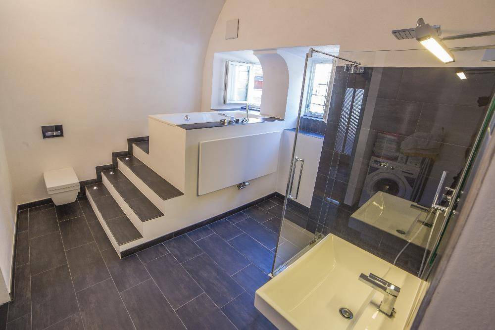 Helles modernes Badezimmer mit Toilette, begehbarer Dusche und erhöhter Badewanne.