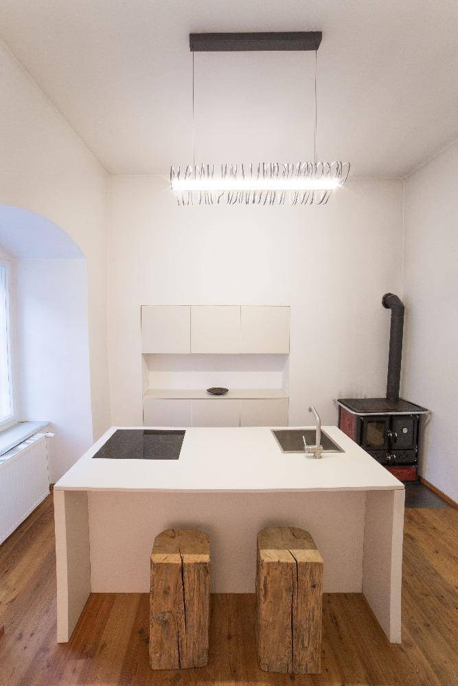 Moderne Küche mit Kochinsel, Spüle und traditionellem Holzofen.