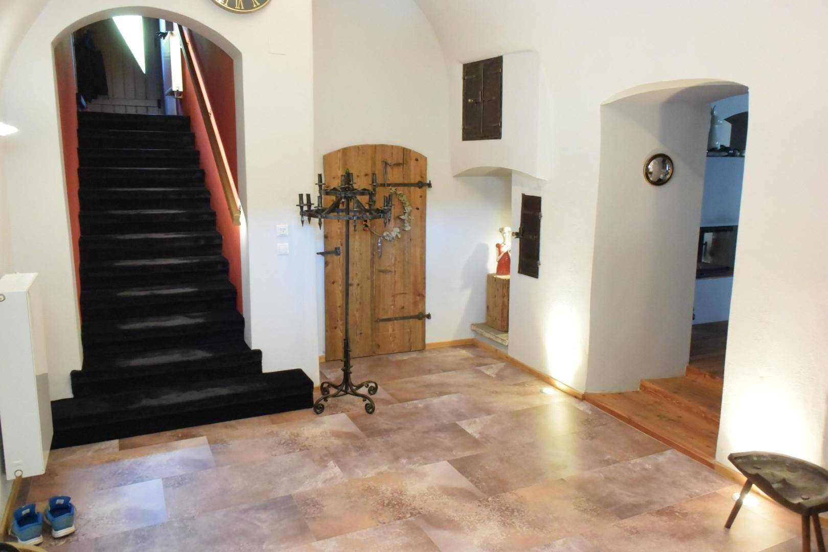 Geräumiger Flur mit dunkler Treppe, Holzboden und traditionellen Türen.