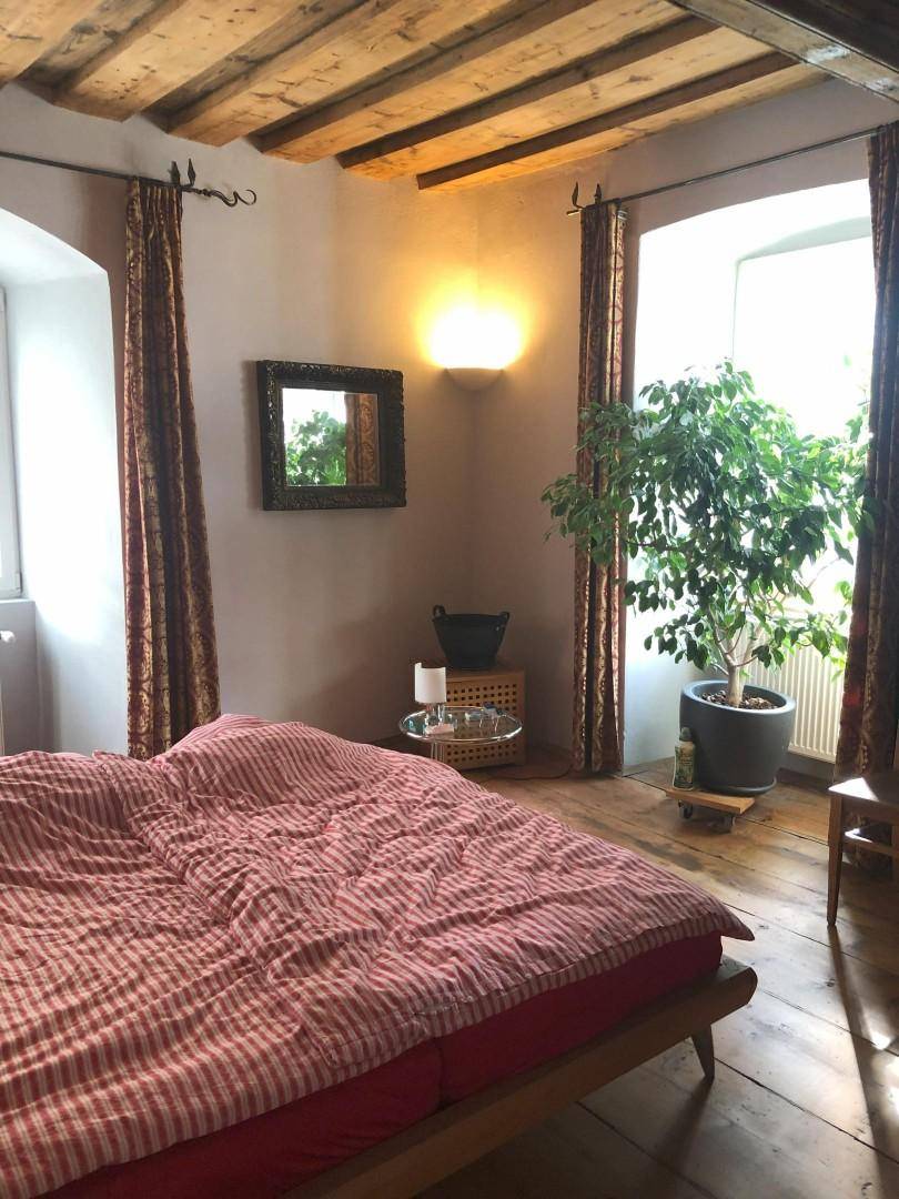 Gemütliches Schlafzimmer mit Holzbalkendecke, Doppelbett und viel Tageslicht.