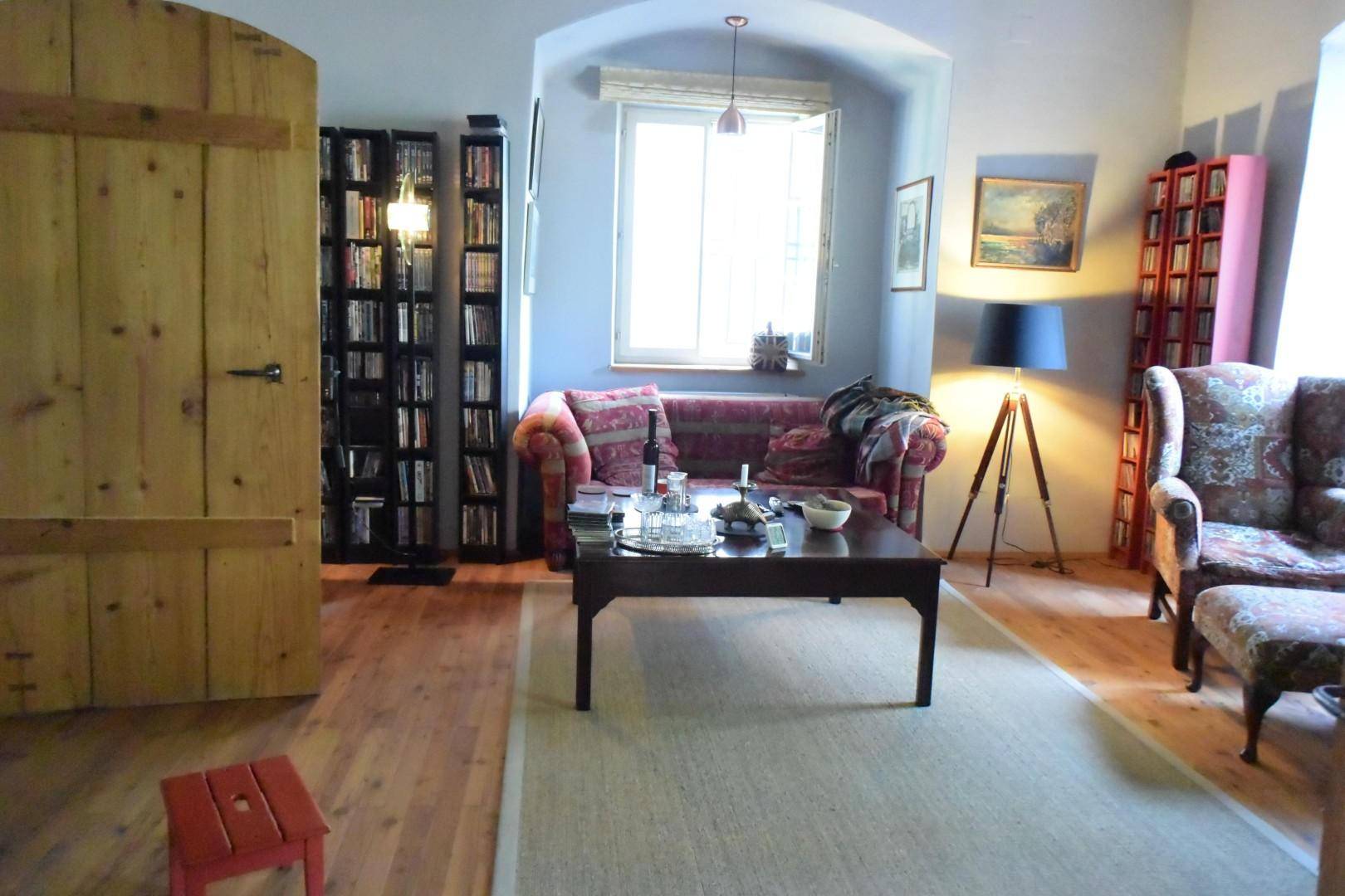 Helles Wohnzimmer mit Holzboden, Bücherregalen und einem bequemen Sofa.