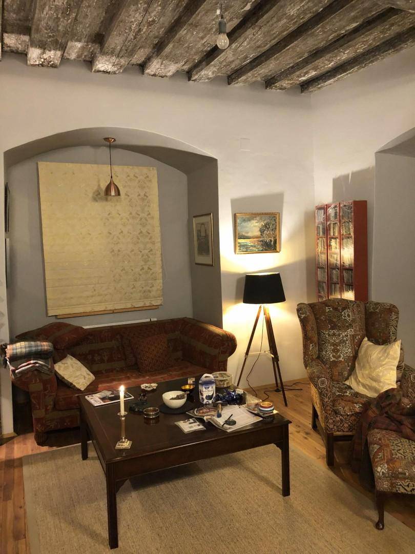 Gemütliches Wohnzimmer mit freiliegenden Holzbalken, traditionellen Möbeln und warmem Licht.