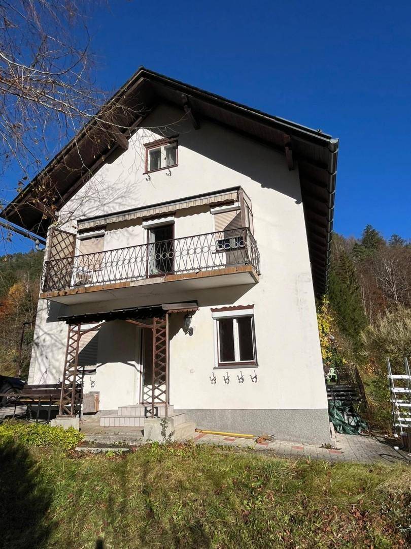 Seitenansicht des Hauses mit Balkon und Blick auf die herbstliche Natur und Berge.