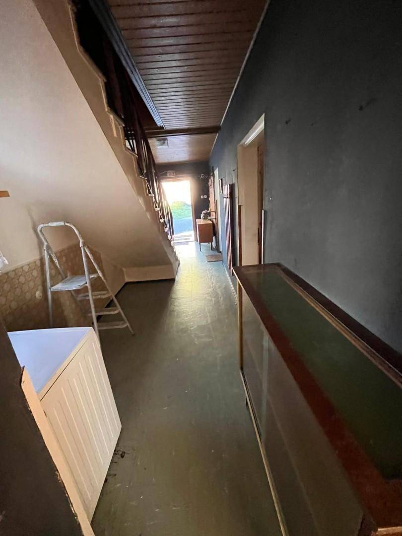 Langer Flur mit Treppe und Holzdecke, führt zu einem hellen Ausgang, gut beleuchtet.