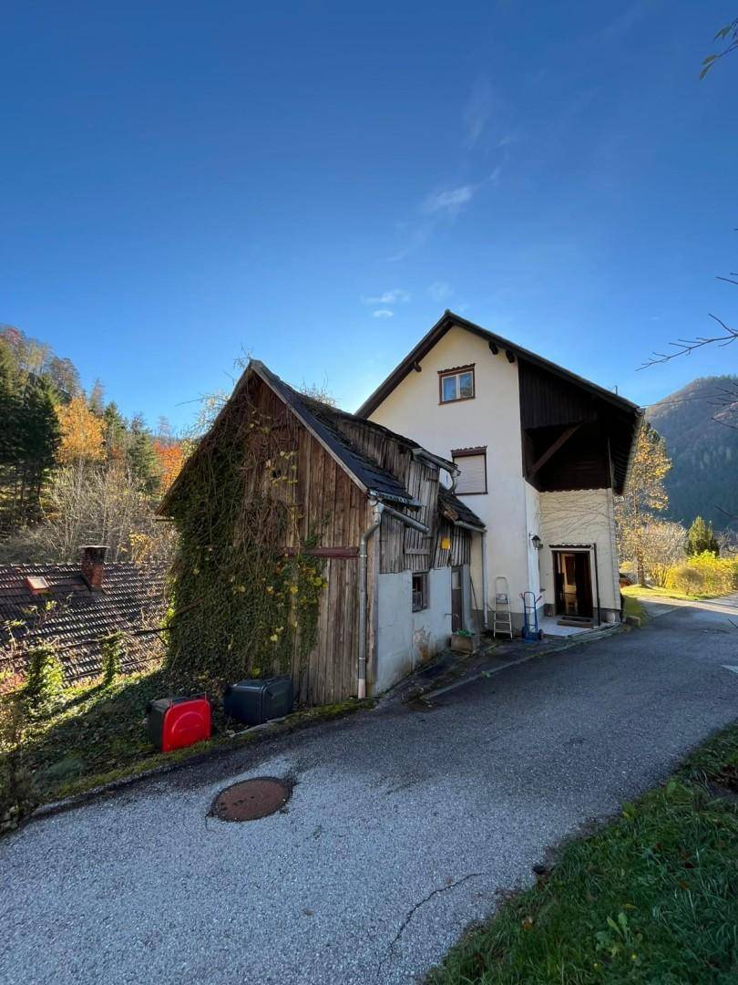 Rückansicht des Hauses mit Anbau und Zufahrtsstraße, umgeben von herbstlicher Landschaft.