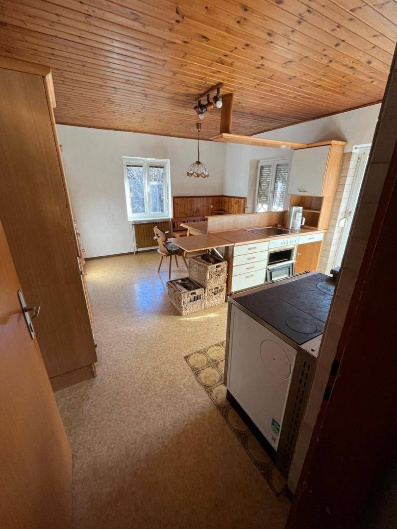 Geräumige Küche mit Holzdecke, Essbereich und traditionellem Holzofen, hell und funktional.