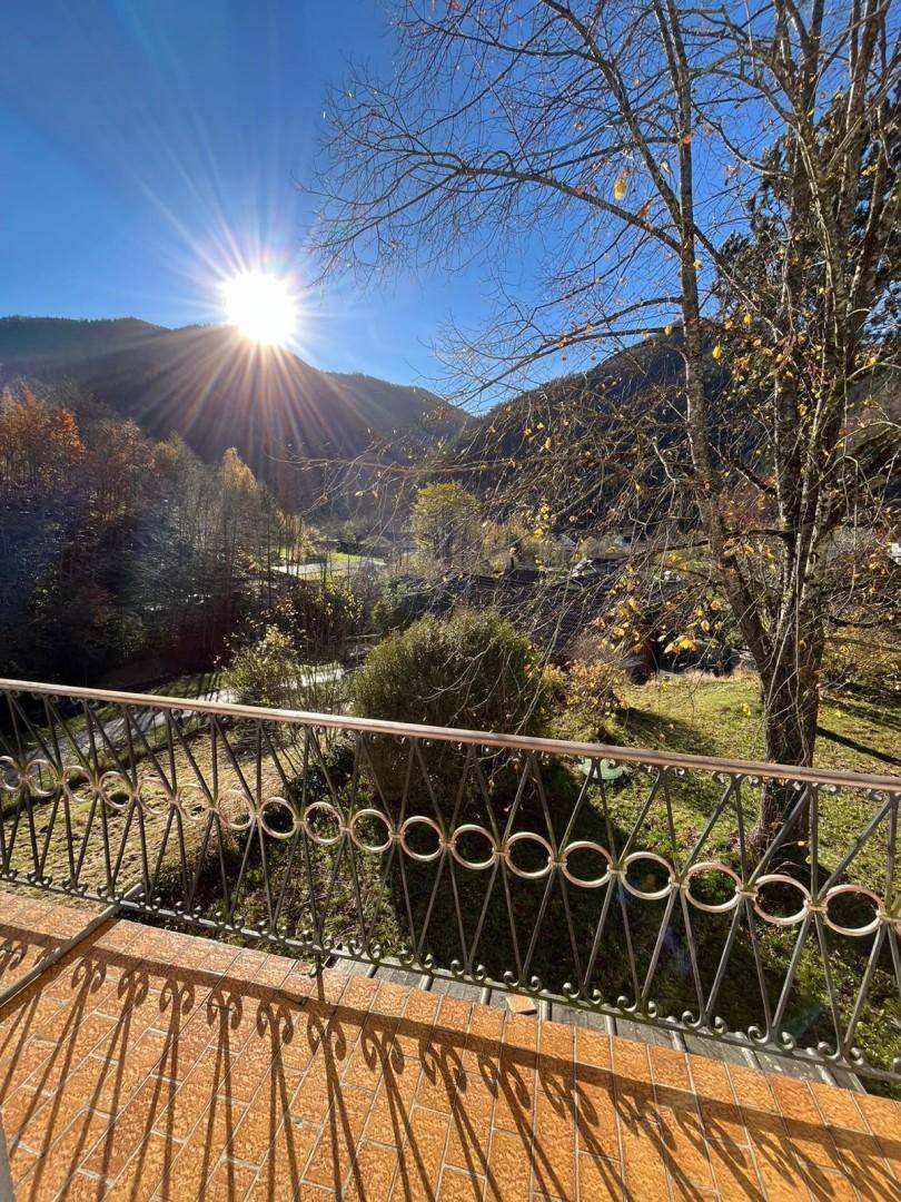 Sonniger Balkon mit Terrakottafliesen und weitem Blick auf die Berge und das Tal.