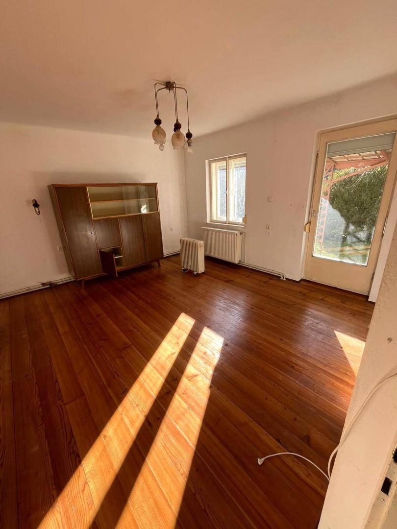 Helles Zimmer mit Holzdielenboden, großem Fenster und Zugang zum Außenbereich, vielseitig nutzbar.