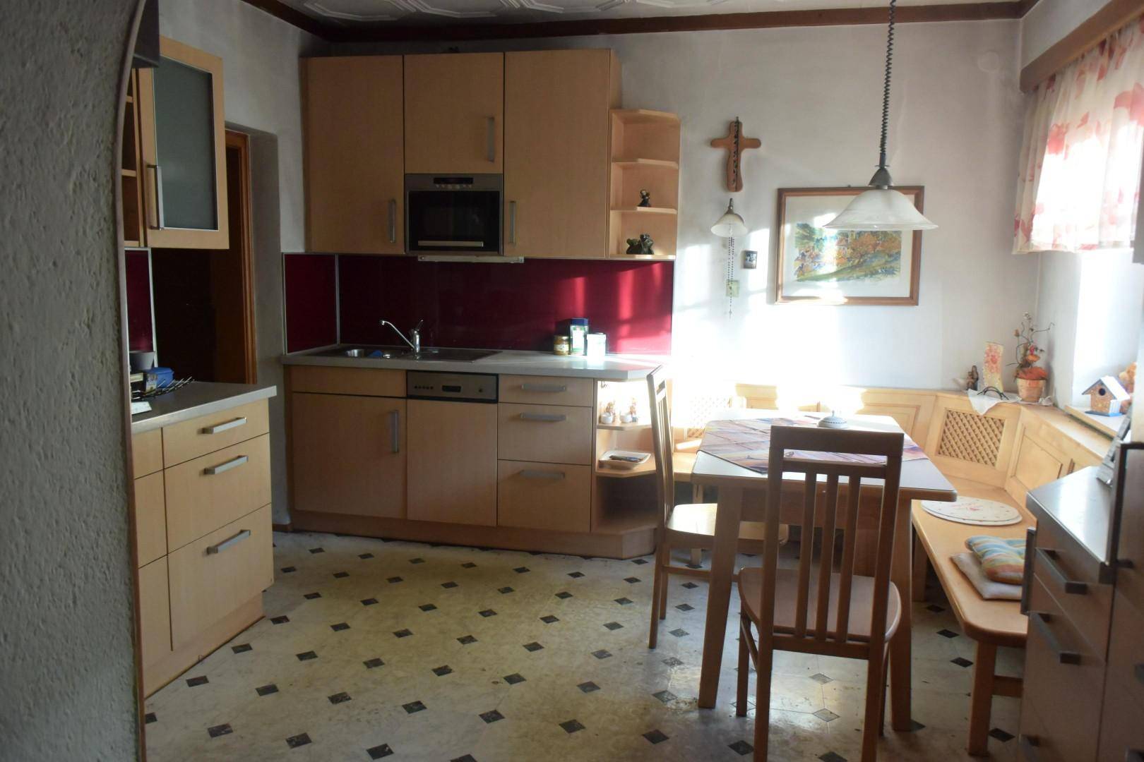 Gemütliche Küche mit Holzeinbauten, Essbereich und traditionellem Linoleumboden.