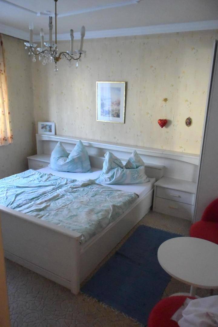 Helles Schlafzimmer mit Doppelbett, Teppichboden und Kronleuchter in klassischem Stil.