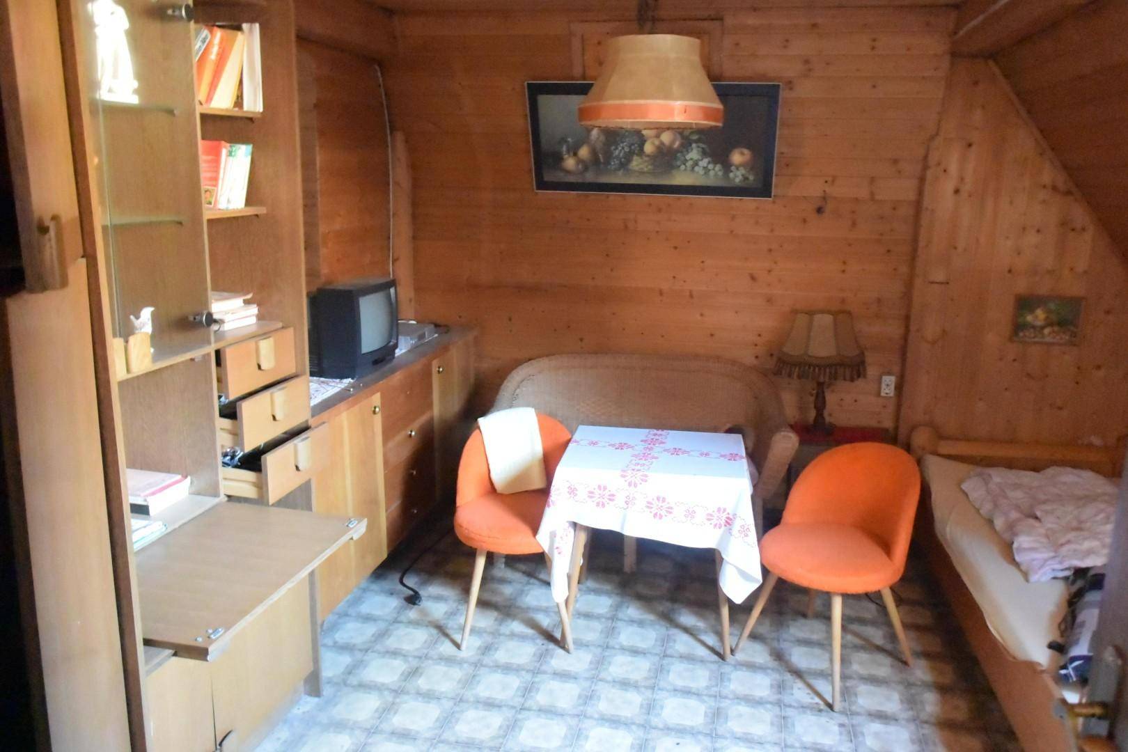Rustikales Zimmer mit Holzvertäfelung, Einzelbett und kleinem Tisch.