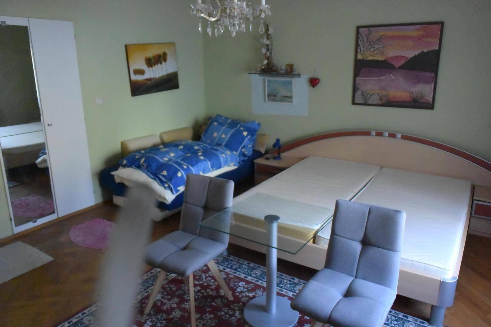 Geräumiges Schlafzimmer mit zwei Einzelbetten, Teppich und hellgrünen Wänden.