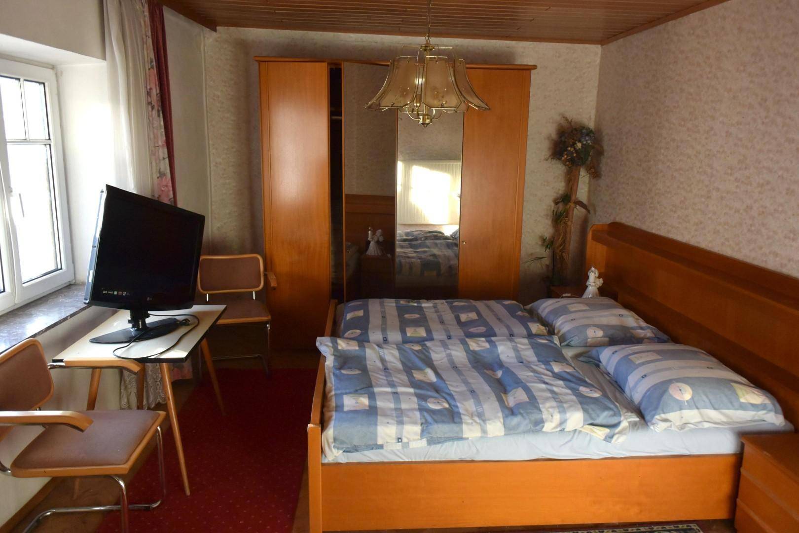 Schlafzimmer mit Doppelbett, Holzschrank und Teppichboden in traditionellem Stil.