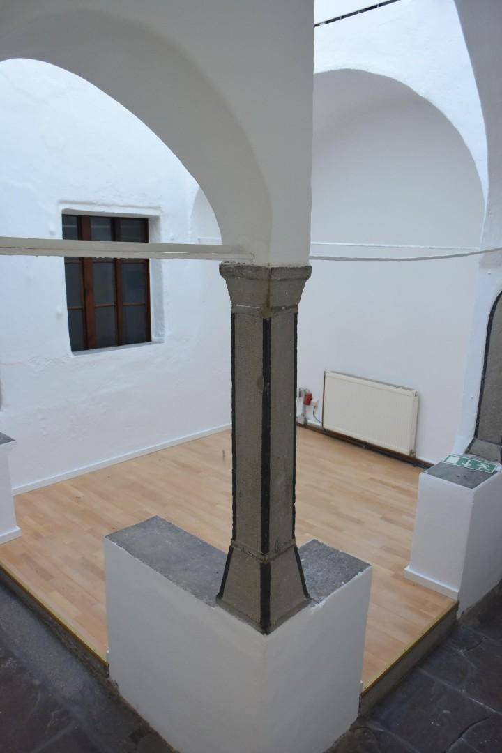 Historischer Innenbereich mit markanten Gewölbedecken, einer zentralen Säule und einem neuen Holzdielenboden.