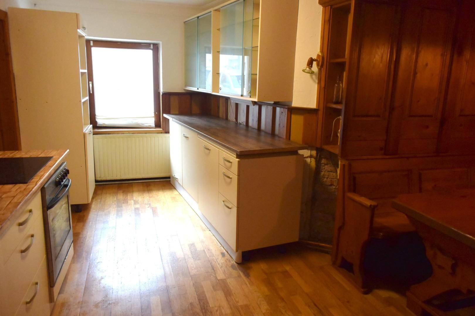 Helle Küche mit Fenster, modernen Unterschränken und traditionellem Essbereich.