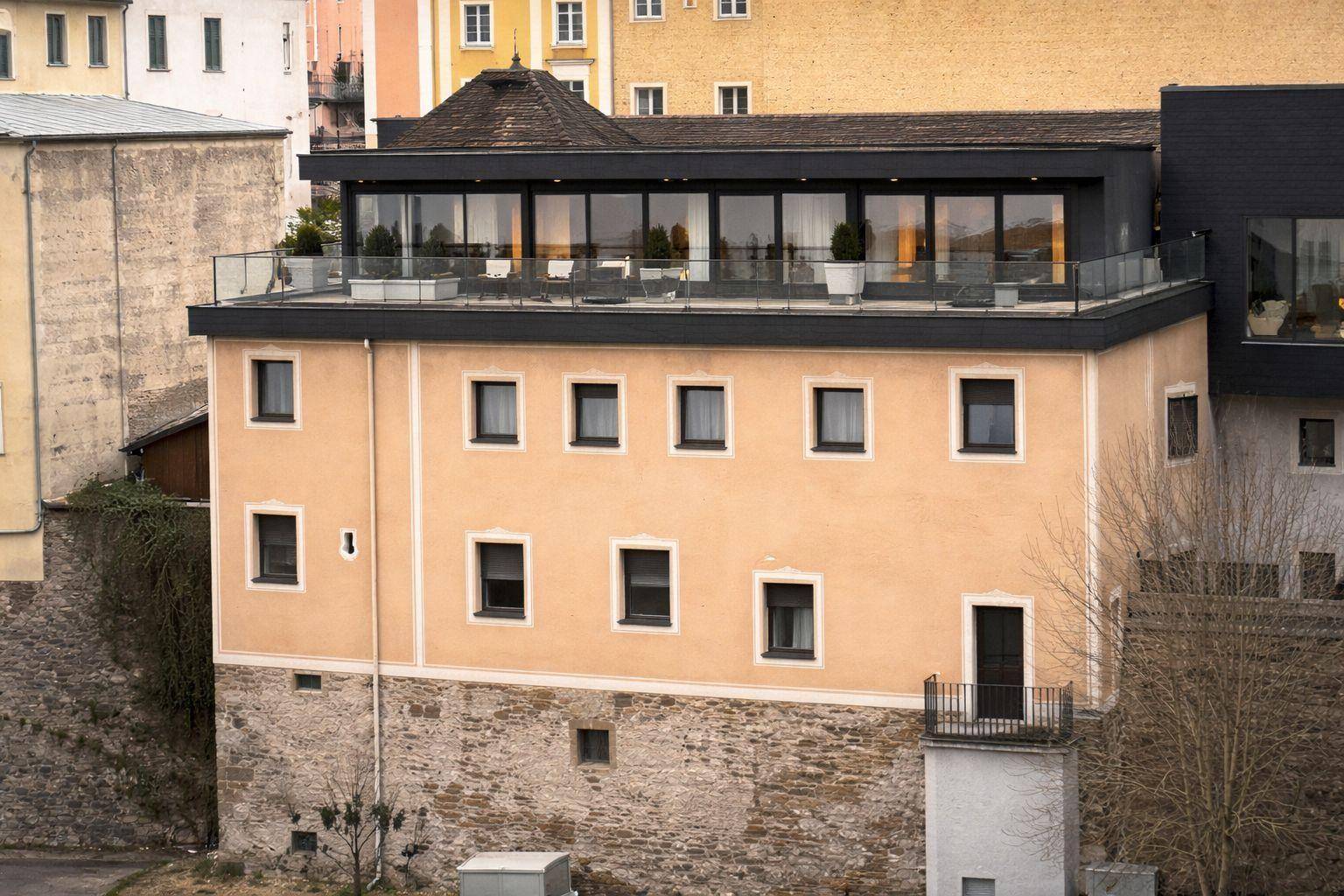 Große Dachterrasse mit Glasgeländer und Sitzgelegenheiten auf einem historischen Gebäude.