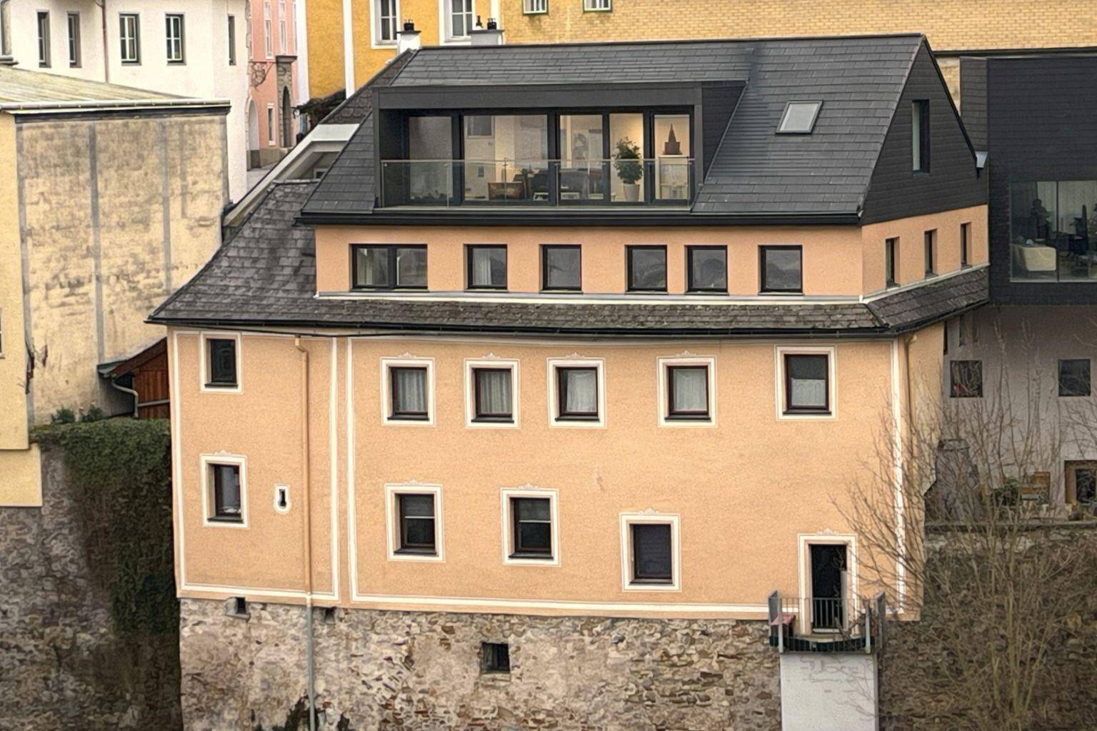 Historisches Gebäude mit modernem Dachausbau, Glasfassade und einer Dachterrasse.