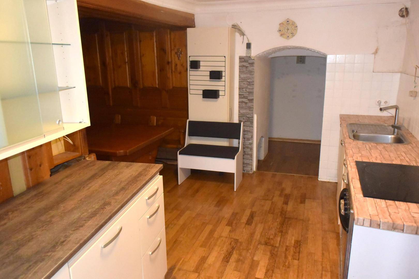 Küche mit Holzboden, modernen Unterschränken und Blick auf den traditionellen Essbereich.