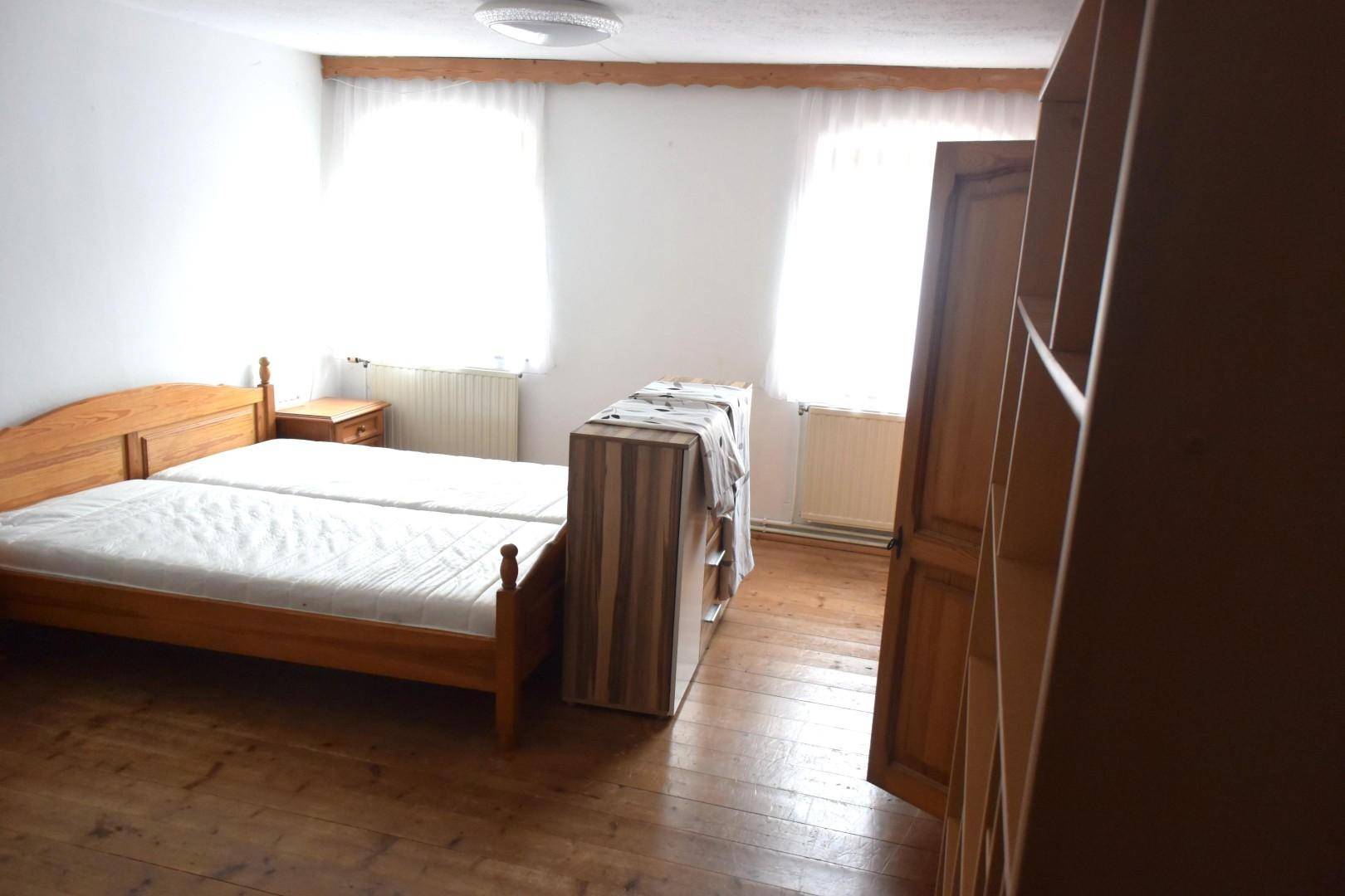 Schlafzimmer mit Holzboden, zwei Einzelbetten und einem Holzschrank im traditionellen Stil.