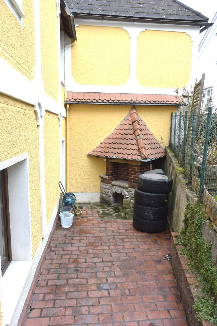 Gepflasterter Außenbereich mit Ziegelsteinen und einem gemauerten Ofen mit Ziegeldach.