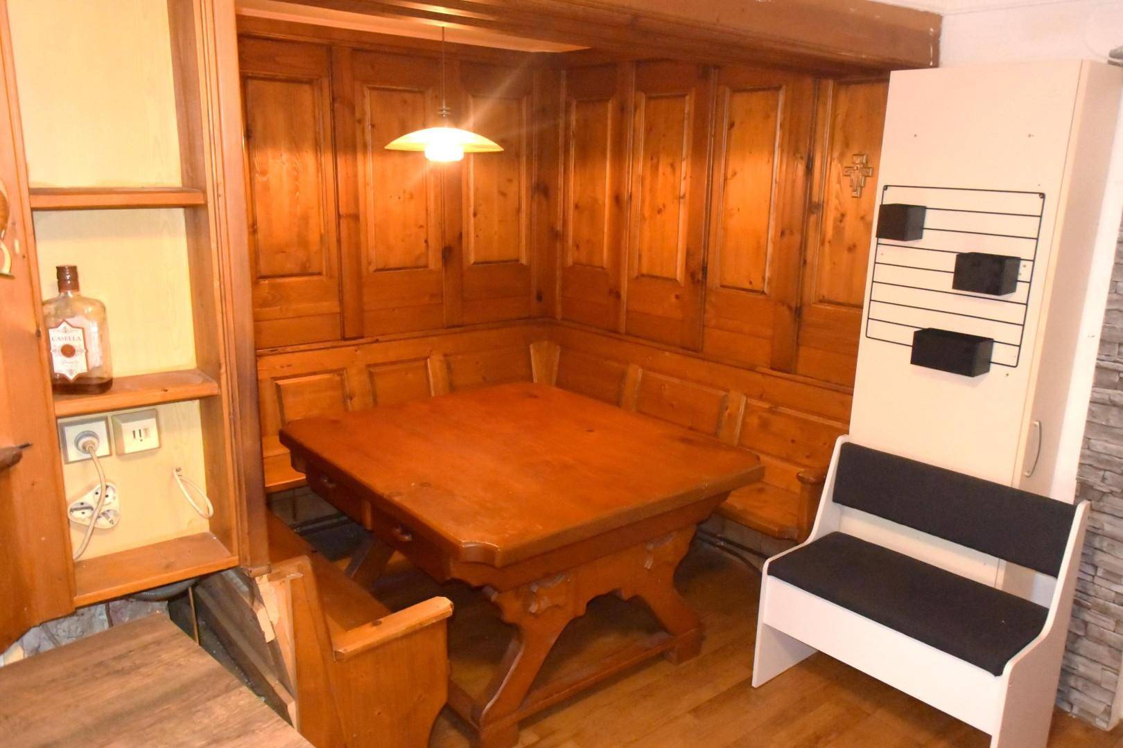 Rustikaler Essbereich mit Holztäfelung, eingebauten Bänken und einem großen Holztisch.