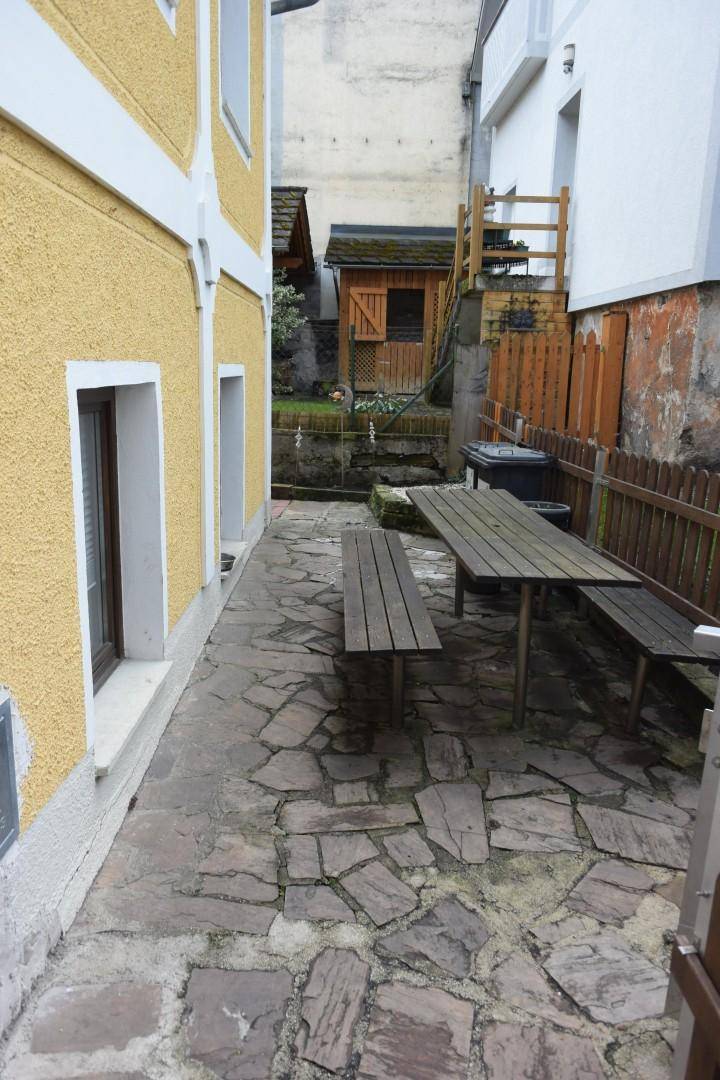 Außenbereich mit Natursteinpflaster und einer rustikalen Holzbankgarnitur für geselliges Beisammensein.