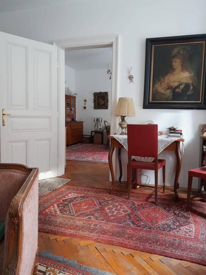 Flur mit Holzboden und rotem Teppich, der den Blick in ein weiteres Zimmer mit klassischer Einrichtung freigibt.