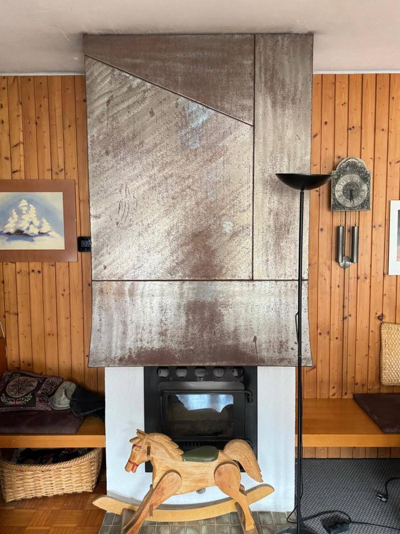 Moderner Kamin mit Metallverkleidung als zentrales Element im rustikalen Wohnbereich.
