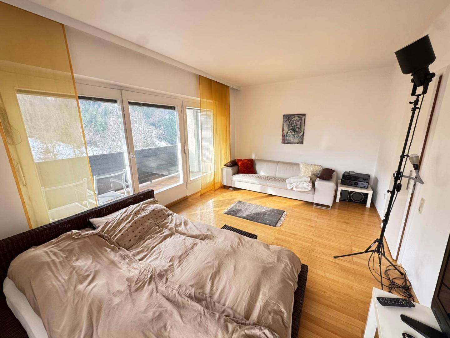 Helles Schlafzimmer mit Holzboden, großem Bett und Zugang zu einem Balkon mit Aussicht.