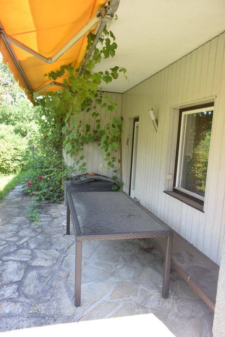 Sonniger Terrassenbereich mit ausziehbarer Markise und einem Tisch, ideal für Mahlzeiten im Freien.