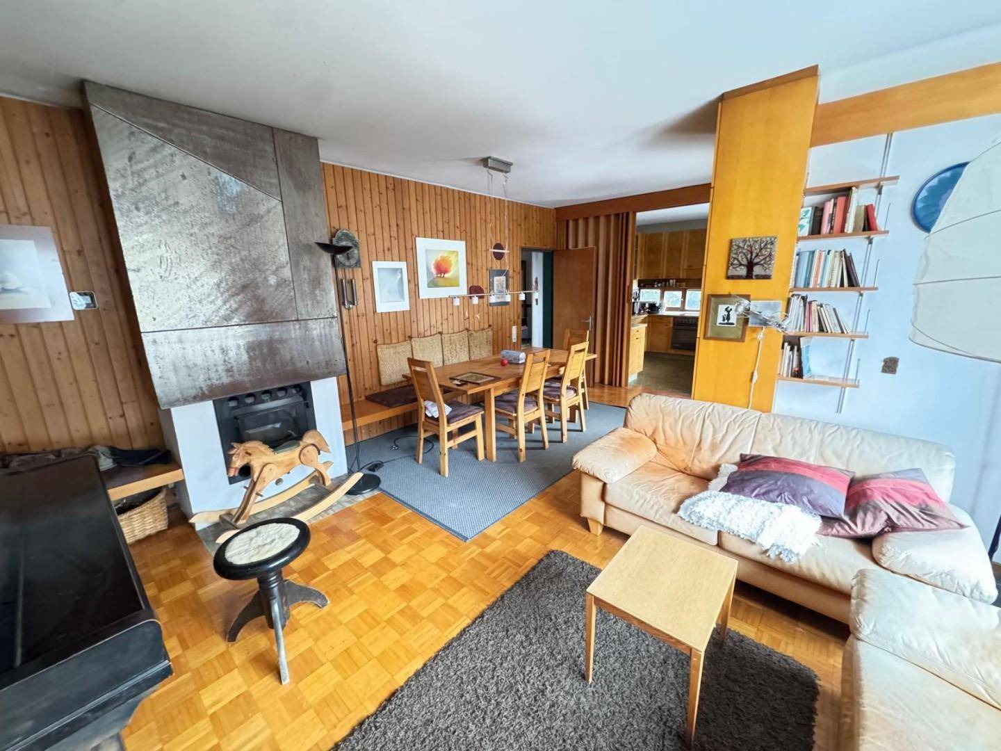 Rustikaler Wohn-Essbereich mit Kamin, Holzwänden und Parkettboden, ideal für gesellige Abende.