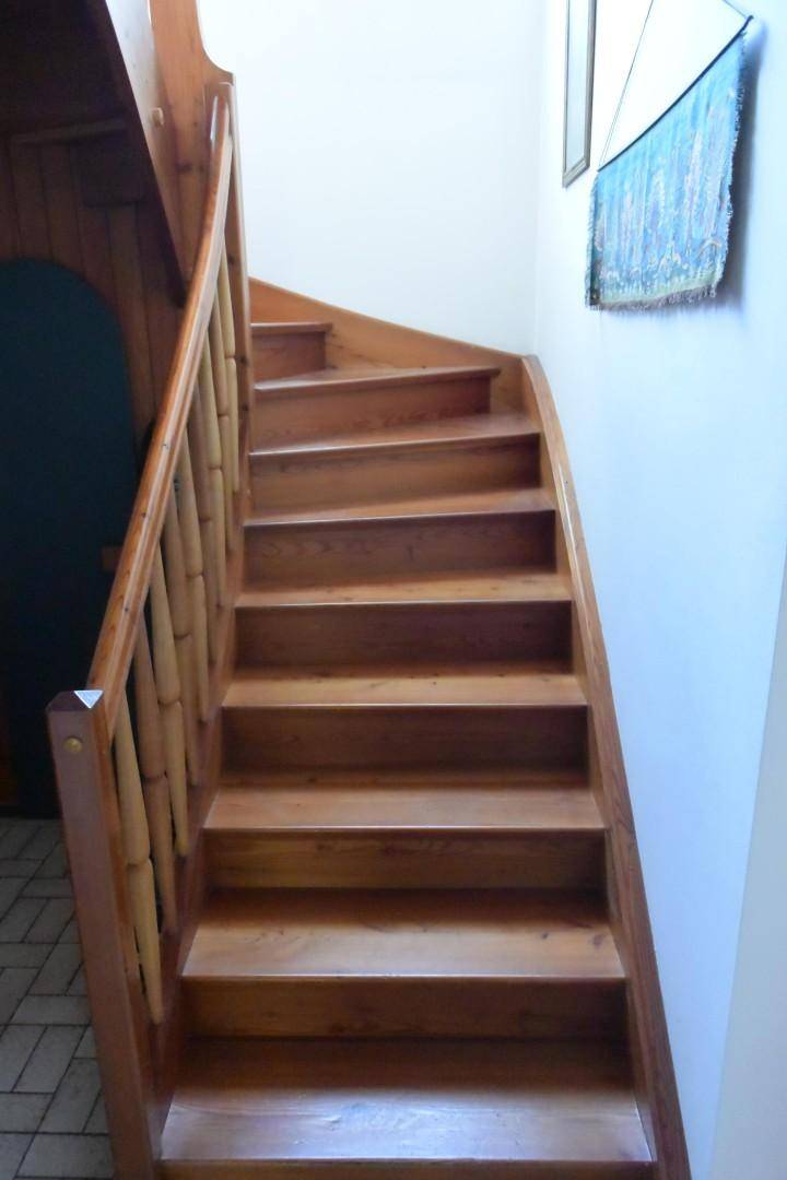 Holztreppe mit Geländer, die die verschiedenen Ebenen des Hauses miteinander verbindet.