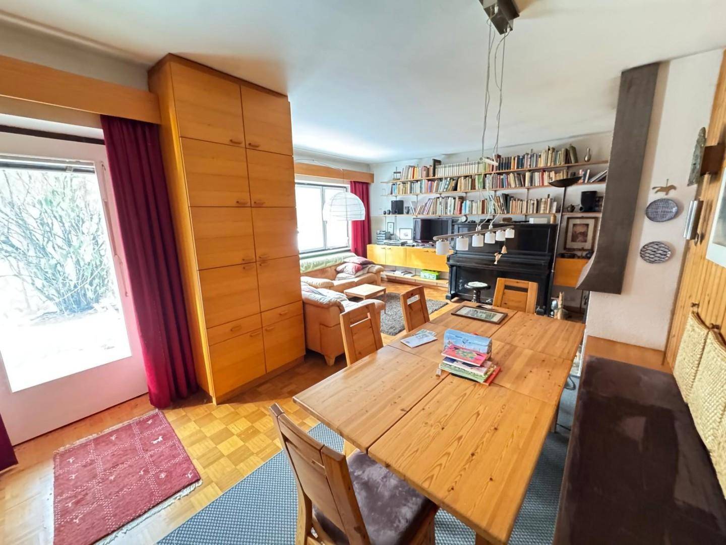 Heller Wohn- und Essbereich mit Holzboden, Einbauschränken und Zugang zu einem Balkon.