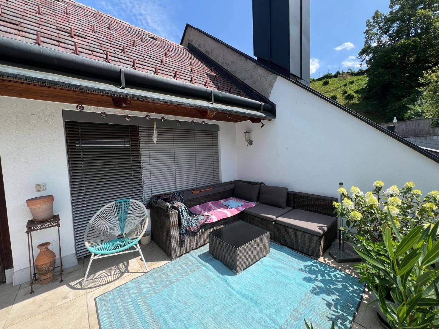 Geräumige Terrasse mit Lounge-Möbeln und Pflanzen, ideal zum Entspannen im Freien.