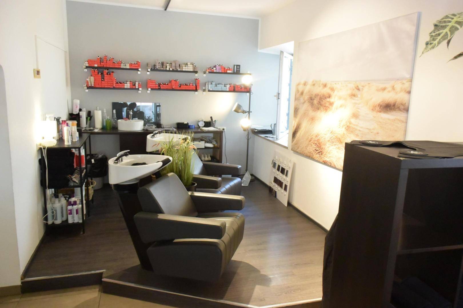 Waschbereich eines Salons mit dunklem Boden und großem Wandbild.