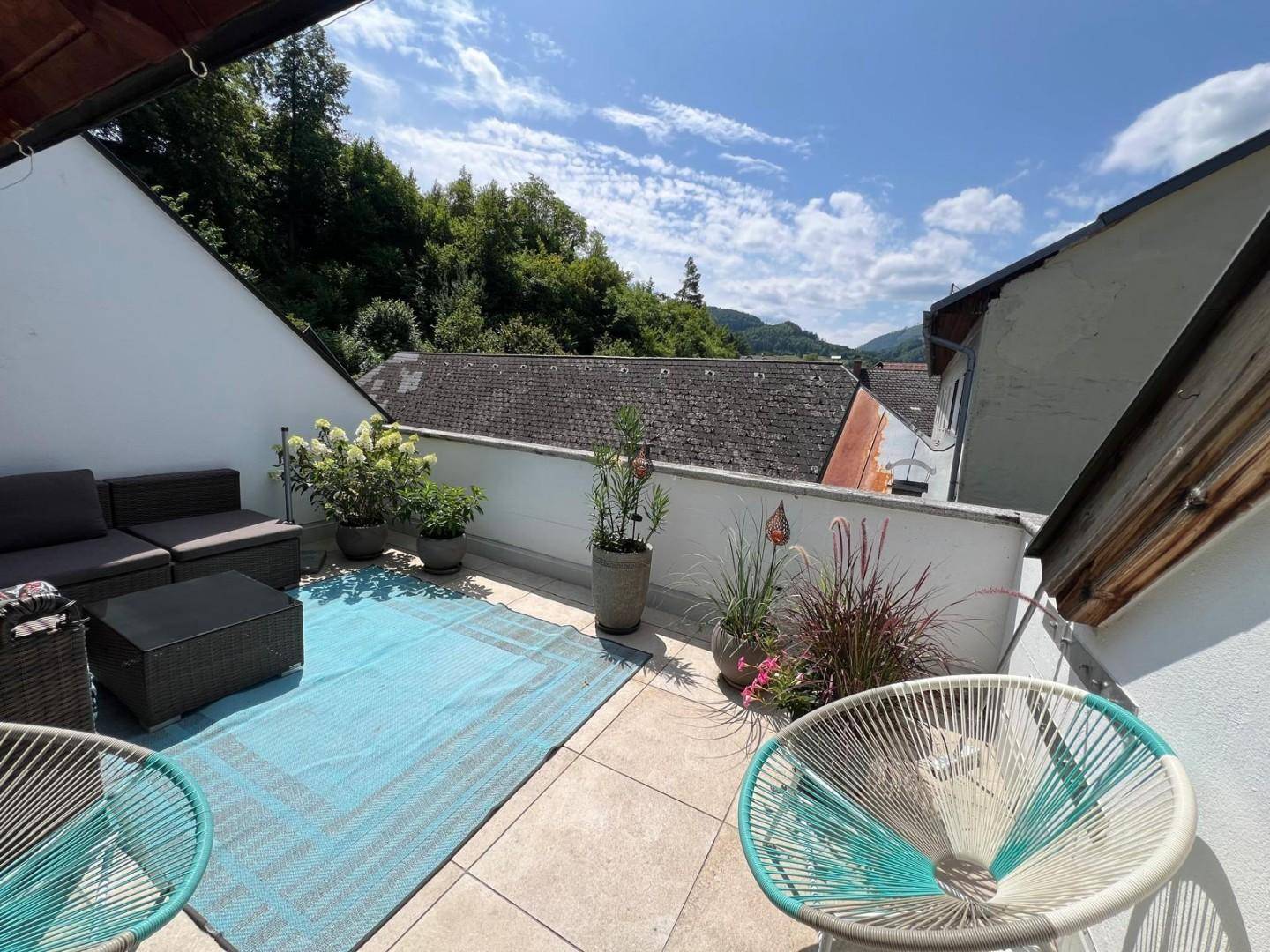 Sonnige Dachterrasse mit Sitzgelegenheiten und weitem Blick auf die grüne Umgebung.