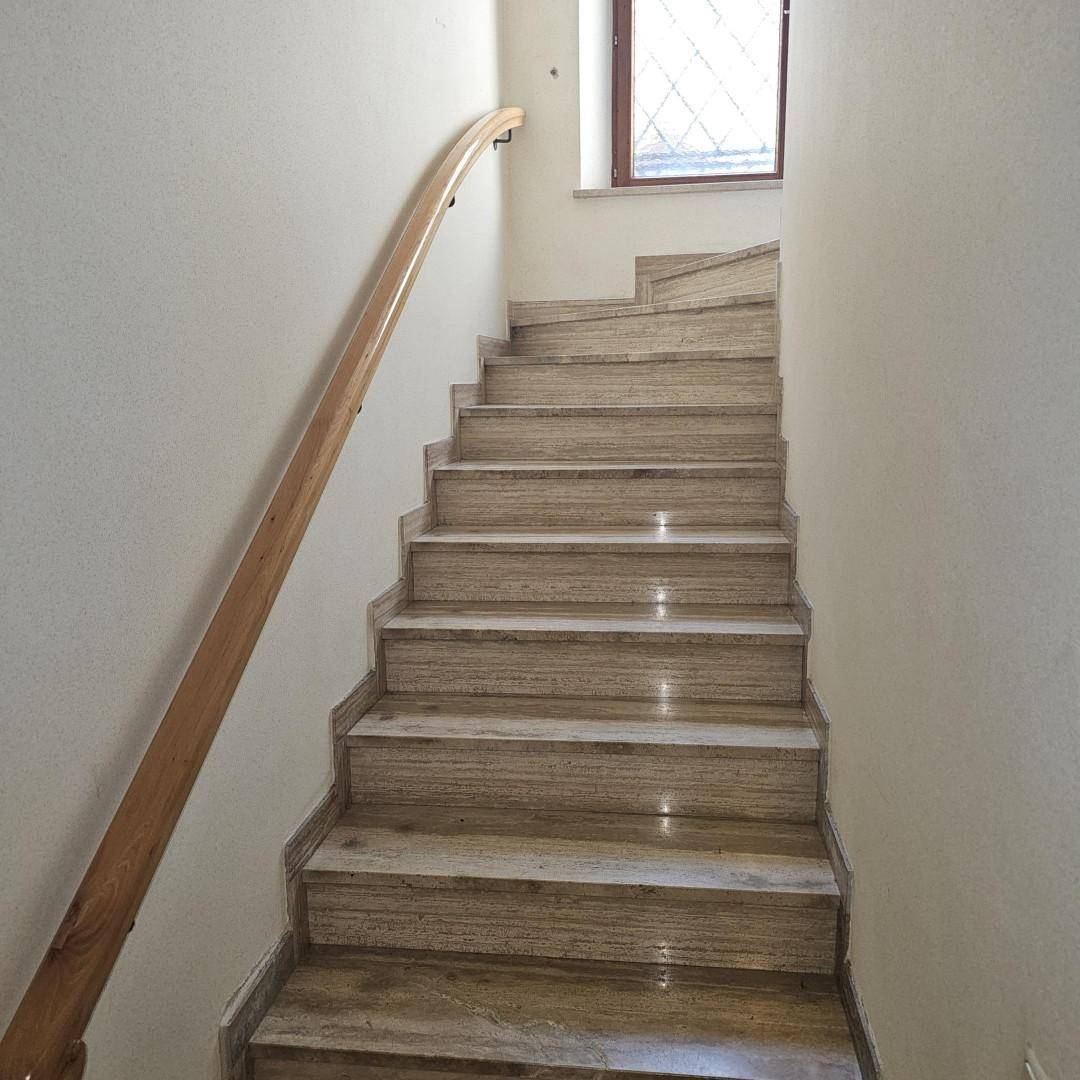 Elegante Steintreppe mit Holzgeländer und Fenster für natürliches Licht.