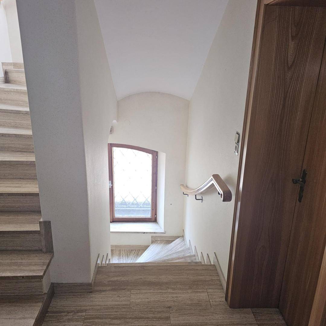 Treppenhaus mit Steinstufen und einem Fenster, das den Bereich erhellt.