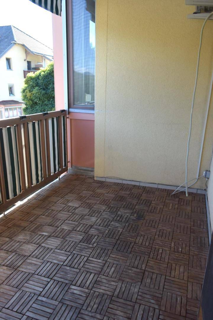 Balkon mit Holzbodenfliesen und Blick auf die Nachbarschaft.