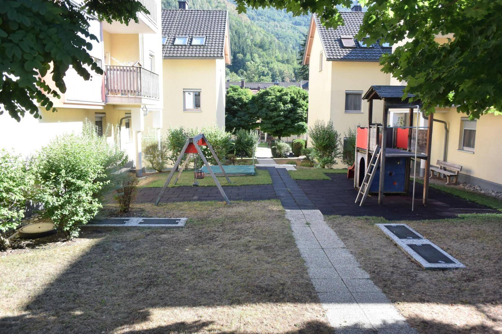 Gemeinschaftlicher Gartenbereich mit Kinderspielplatz und Grünflächen zwischen den Gebäuden.