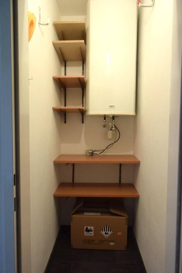 Kleiner Abstellraum mit Regalen und einem Warmwasserboiler.