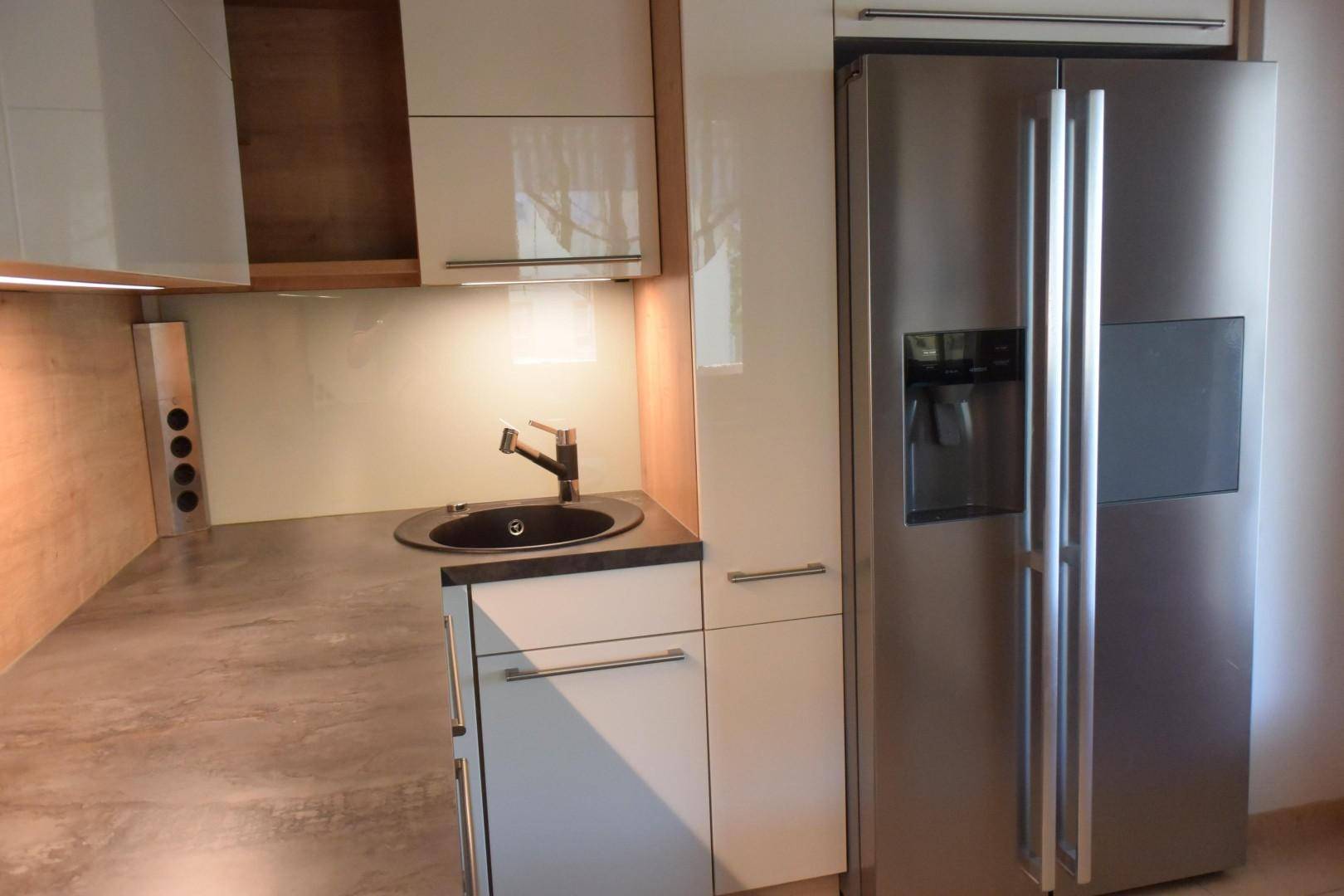 Küchenzeile mit Spülbecken, Arbeitsplatte und großem, modernem Kühlschrank.