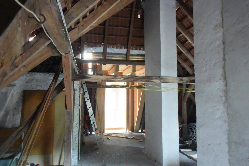 Rohbau-Dachboden mit freiliegenden Holzbalken und Leiter, bietet Ausbaupotenzial.