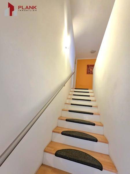 Heller Treppenaufgang mit Holzstufen und modernem Handlauf.