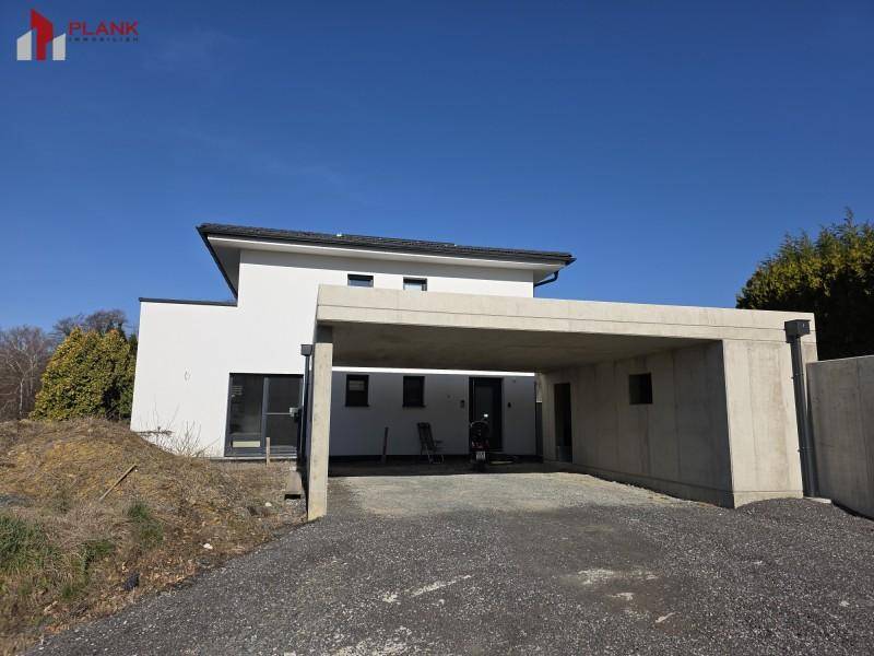 Modernes Einfamilienhaus mit großem Carport und weißer Fassade.