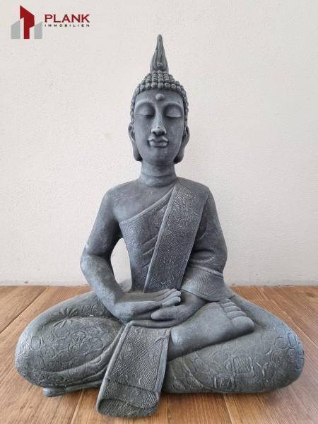 Dekorative Buddha-Statue aus Stein auf einem Holzboden.